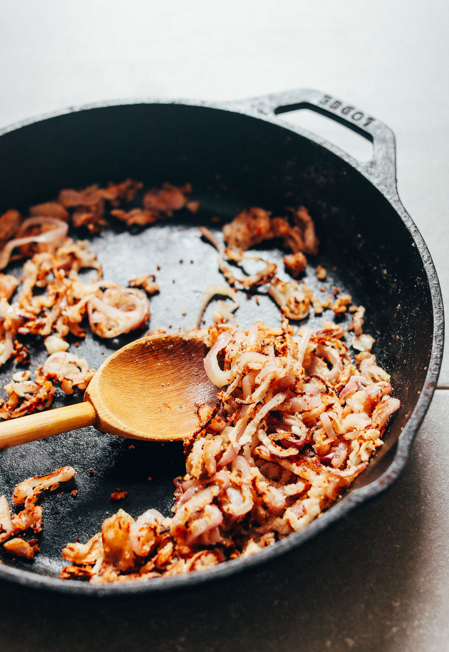 Batch of crispy shallots cooking in a cast-iron skillet