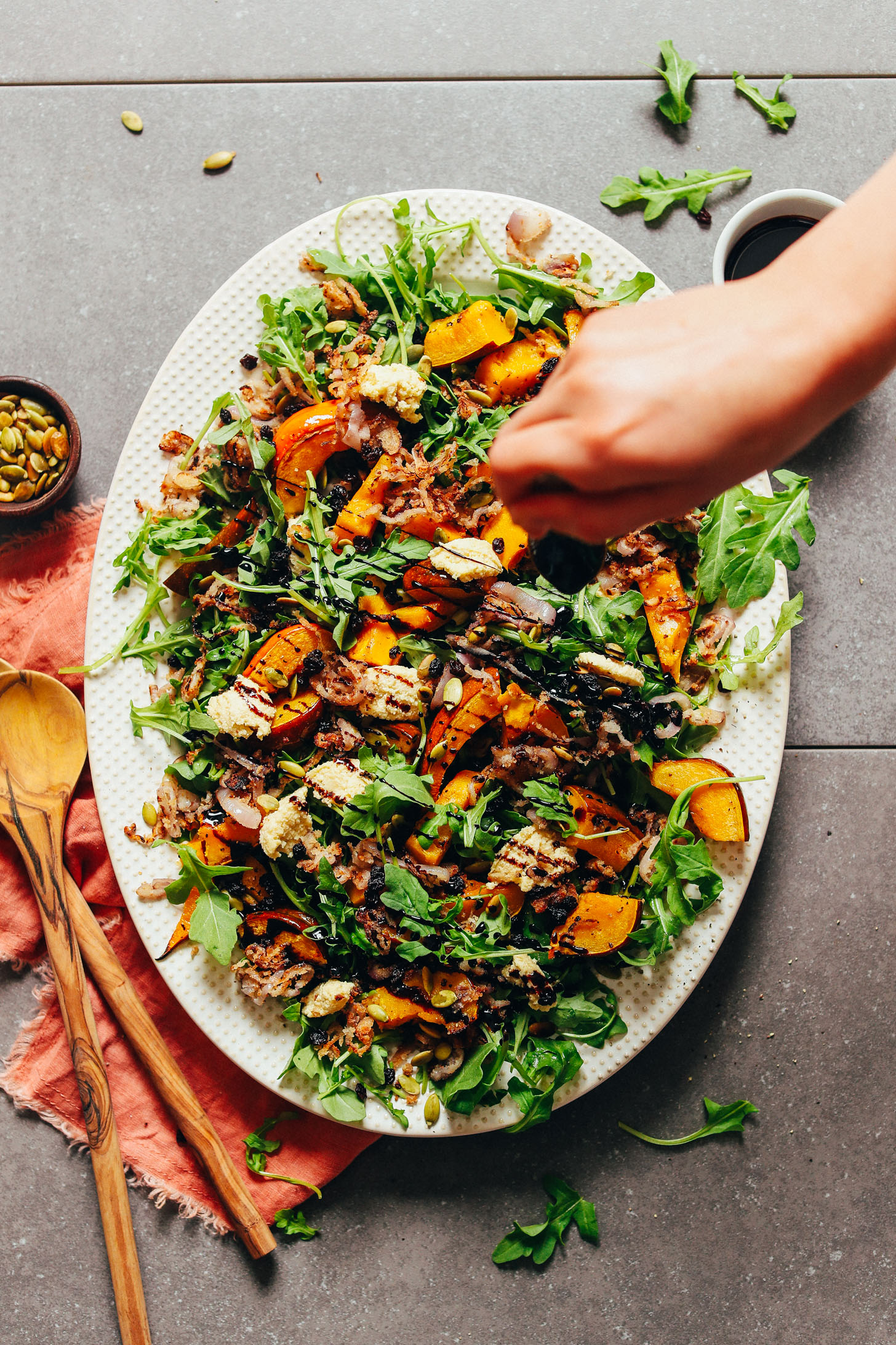 Adding balsamic drizzle over our Roasted Squash Salad with Nut Cheese