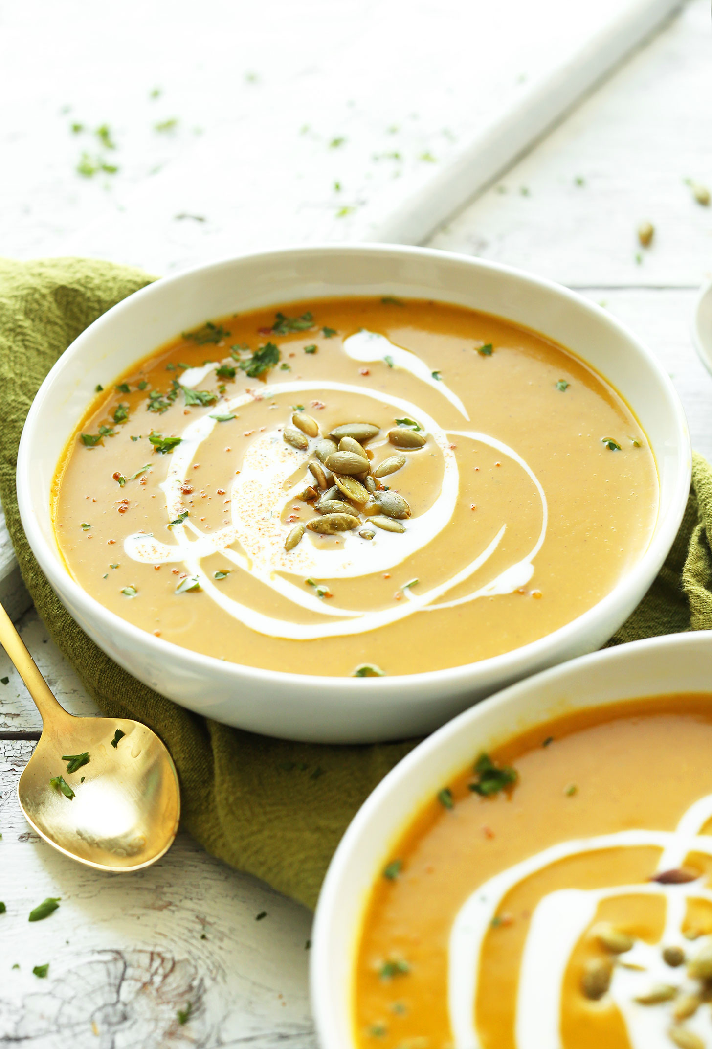 Close up shot of bowls of Curried Butternut Squash Soup with coconut milk and pumpkin seeds