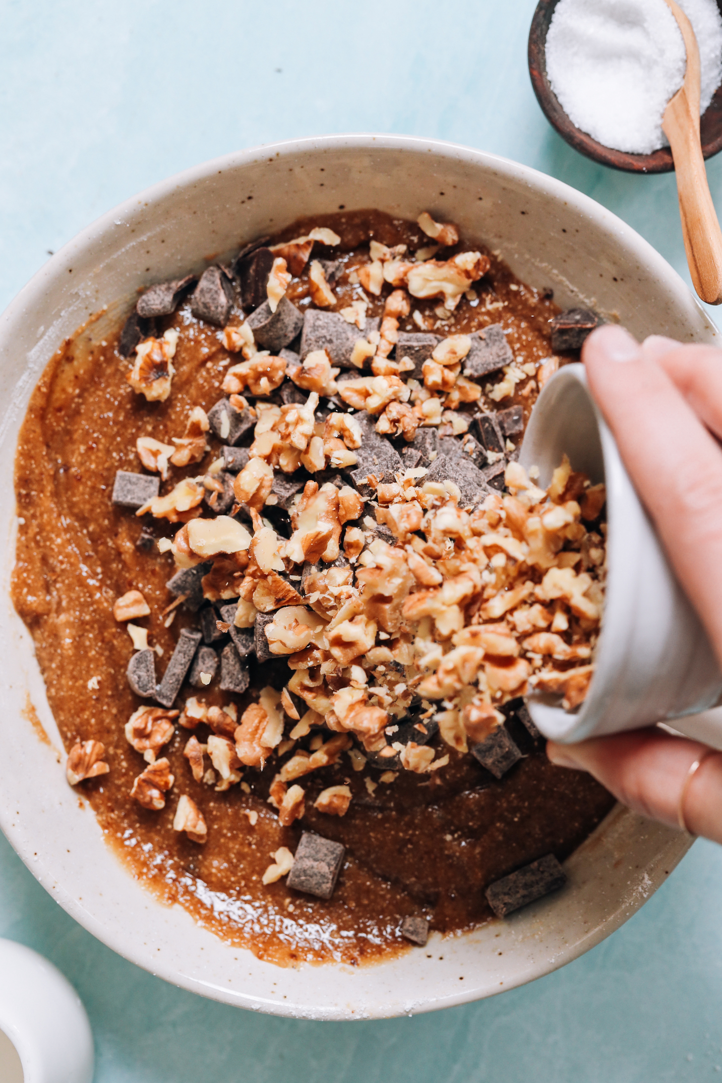 Pouring chopped walnuts and chocolate chips into the cookie dough batter