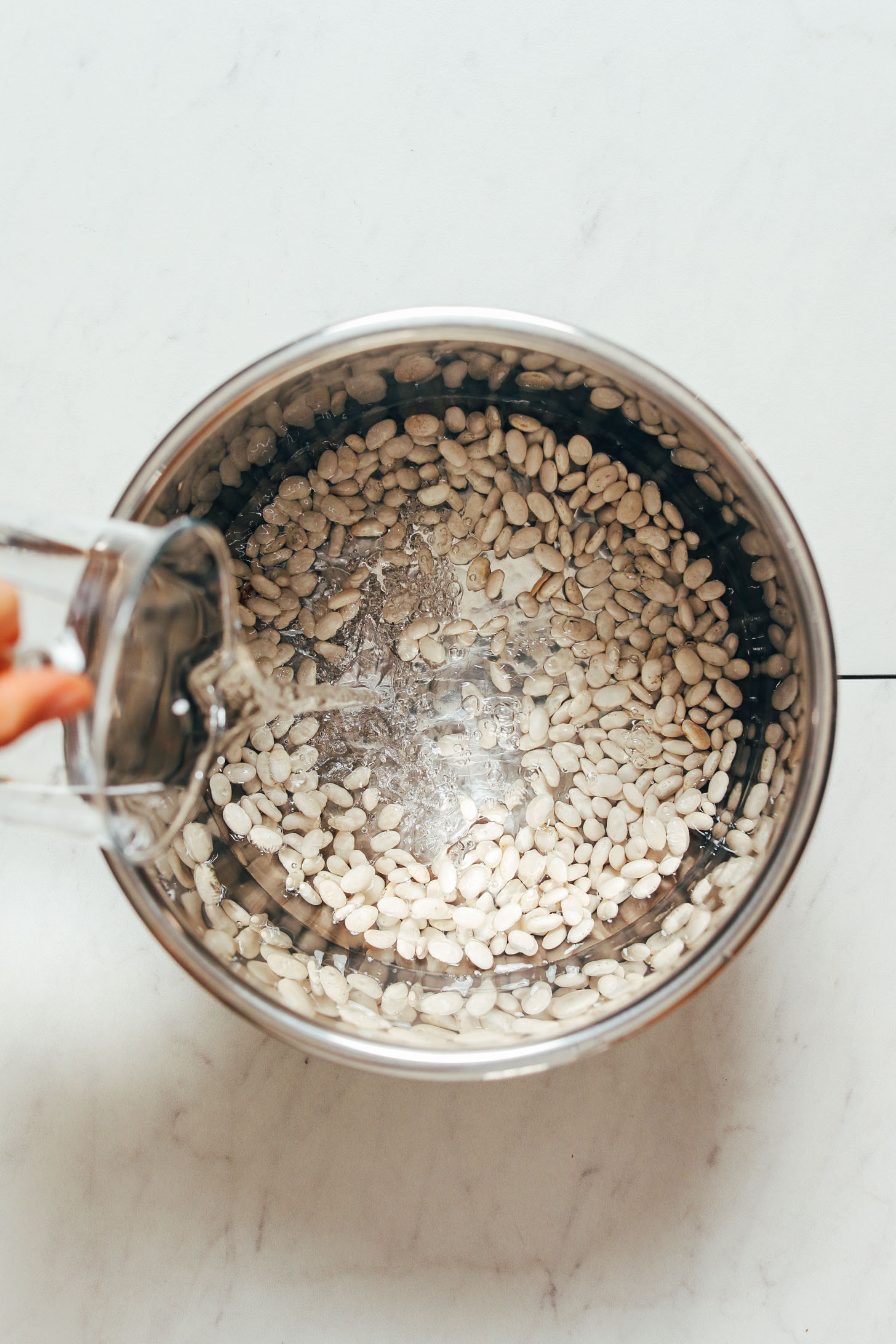 Pouring water over Great Northern Beans in an Instant Pot