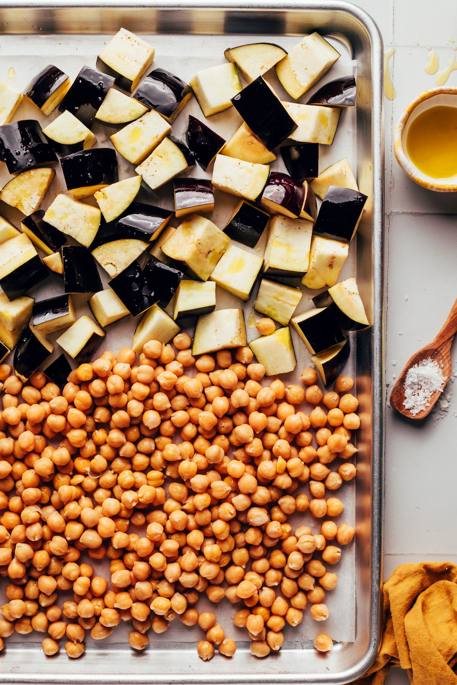 Cubed eggplant and chickpeas on a parchment-lined baking sheet