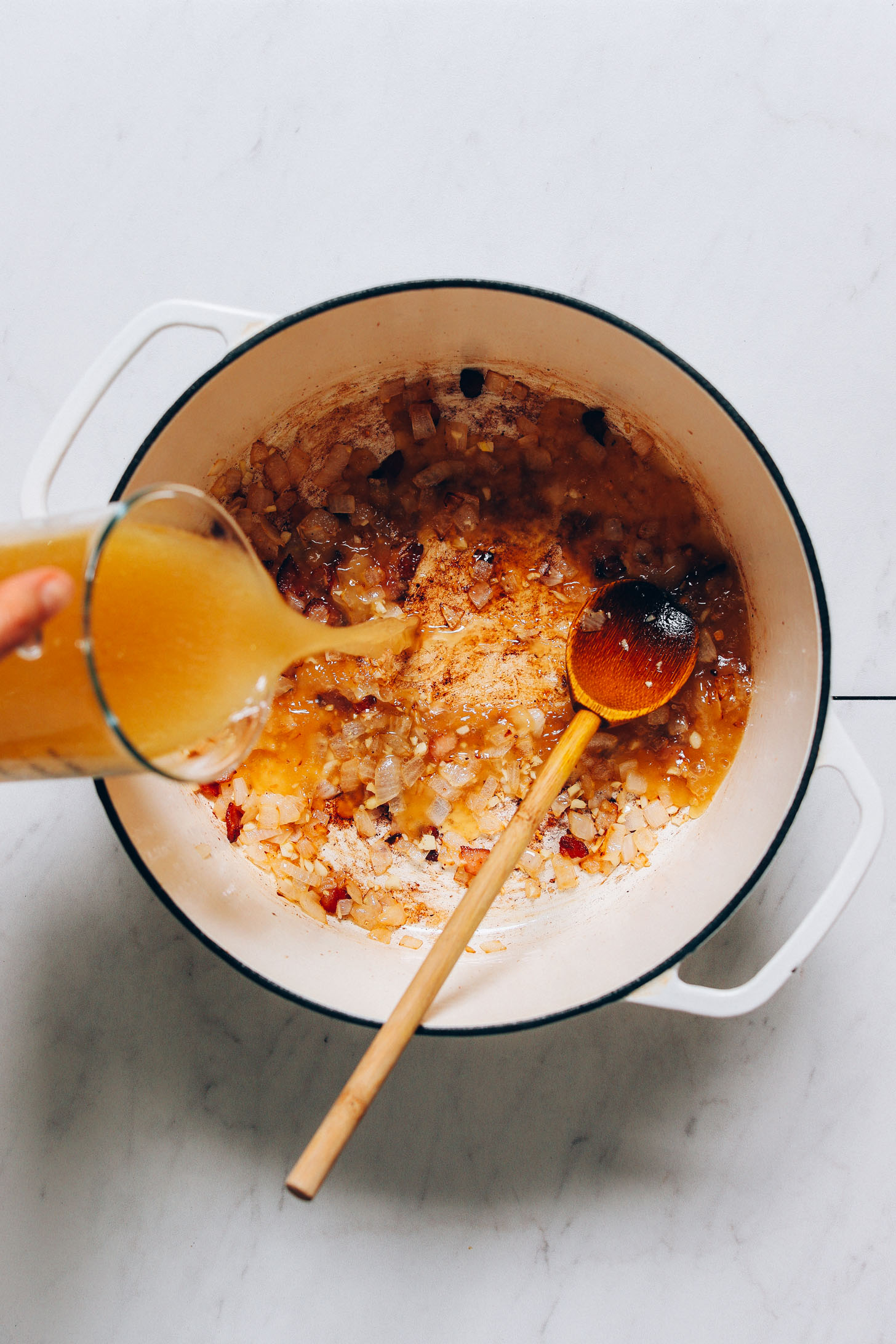 Pouring broth into a large pot to make our Kale White Bean Chicken Soup recipe