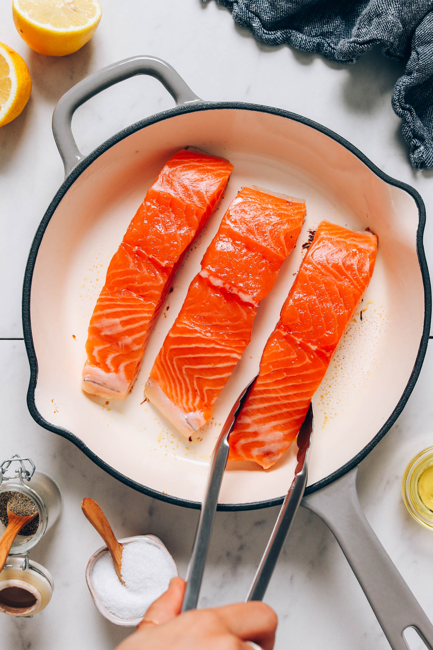 Placing a salmon filet into an enameled cast iron skillet