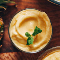 Top down shot of a bowl of pineapple sorbet topped with fresh mint leaves