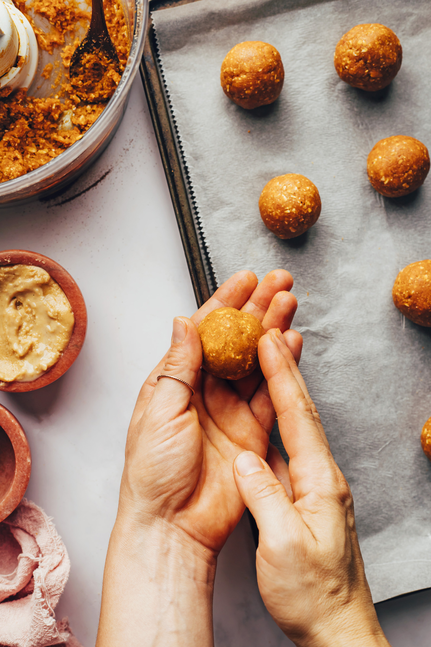 Rolling pumpkin cookie dough into balls to place on a baking sheet