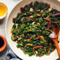 Wooden spoon in a skillet of our easy sautéed swiss chard recipe