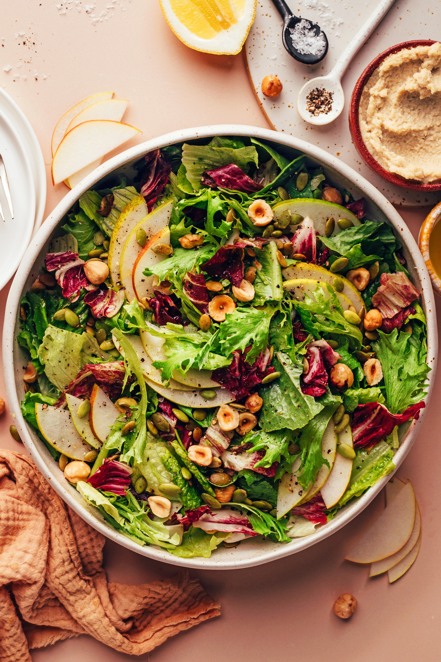 Vegan goat cheese, sliced pears, lemon, salt, and pepper next to a big bowl of our Thanksgiving salad recipe